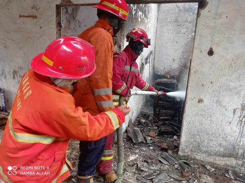 Petugas Damkar saat melakukan pembasahan areal rumah kosong yang terbakar (Ist)