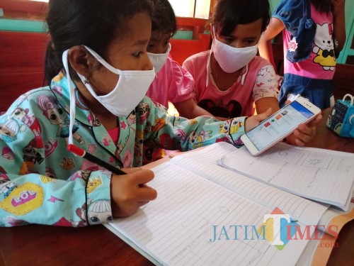 Sejumlah anak terlihat belajar dengan menggunakan satu HP untuk digunakan bersama-sama saat jam belajar daring dimulai. (Foto : Adi Rosul / JombangTIMES)