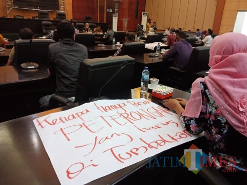 Proses audiensi dengan DPRD Jombang, terlihat salah satu pedagang Pasar Peterongan membawa poster bernada protes. (Foto : Adi Rosul / JombangTIMES)