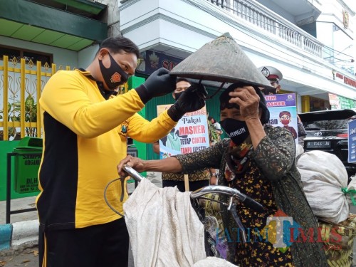 Kapolres saat memakaikan caping setelah memasang masker pada pengguna jalan (Joko Pramono for Jatim TIMES)