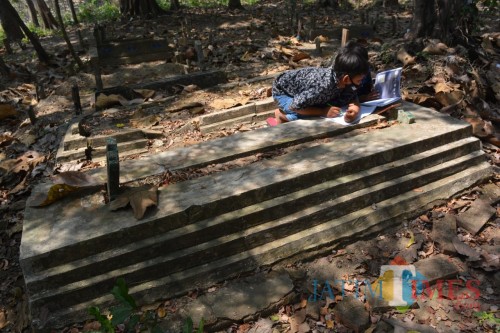 Siswa SDN Sumberaji 2, Kecamatan Kabuh, Jombang terlihat belajar di atas sebuah makam. (Foto : Adi Rosul / JombangTIMES)