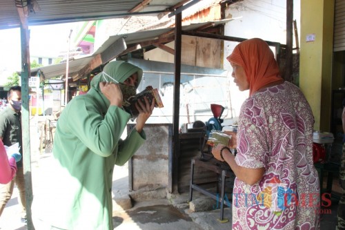 Ketua Bhayangkari cabang Sumenep Risma Saripati saat memberikan masker gratis pada pengunjung pasar (Foto: Ist/JatimTIMES)