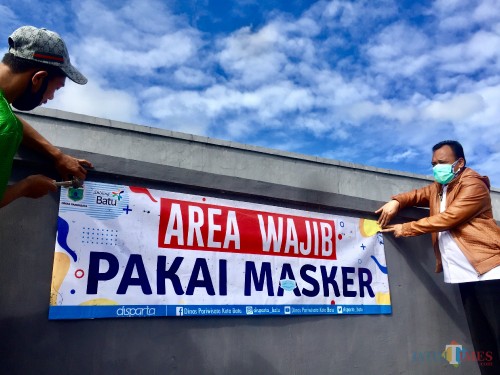 Kepala Dinas Pariwisata Kota Batu Drs. Arief As Siddiq, MH saat memasang imbauan area wajib pakai masker di Sendratari, Jalan Sultan Hasan Halim, Kelurahan Sisir, Kecamatan Batu. (Foto: Irsya Richa/MalangTIMES)