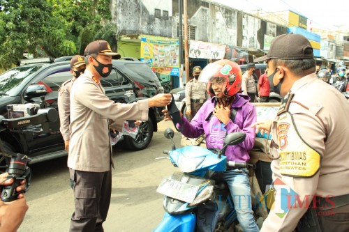 Kapolres Jember AKBP. Aris Supriyono saat membagikan masker kepada pengendara di sekitar pasar Tanjung Jember (foto : istimewa / Jatim TIMES)