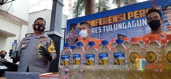 Rimba (masker hitam) saat rilis di Mapolres Tulungagung, nampak Kapolres tunjukan ciu yang dilabeli oleh Rimba (Joko Pramono for JatimTIMES)