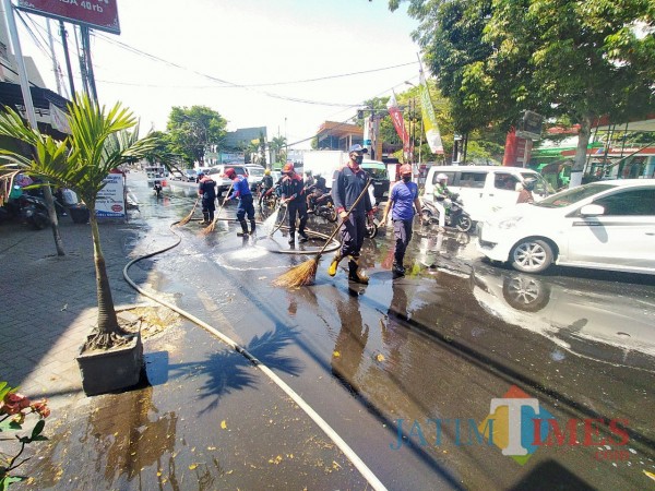 Petugas PMK Kita Malang yang tengah berupaya membersihkan jalan dari cecerna solar (Anggara Sudiongko/MalangTIMES)