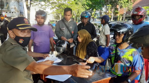 Petugas saat melakukan pendataan kepada sejumlah warga yang melanggar protokol kesehatan dengan tidak memakai masker