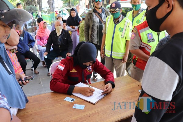 Petugas gabungan saat mengecek identitas warga yang melanggar protokol kesehatan dengan tidak memakai masker (Foto: Ist/JatimTIMES)