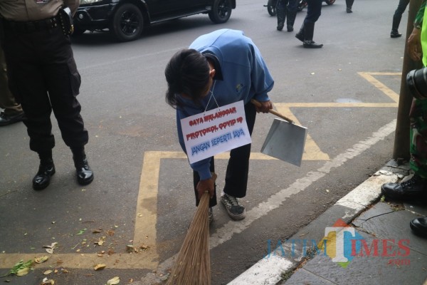 Seorang warga yang dikenai sanksi sosial karena melanggar disiplin bermasker di Kota Malang beberapa waktu lalu. (Ahmad Amin/MalangTIMES).