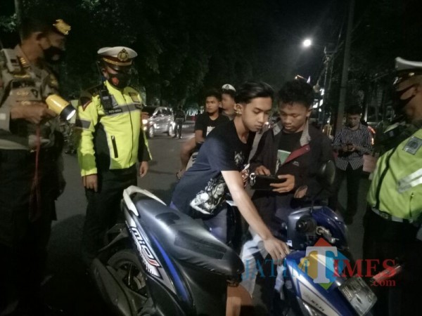 Dua remaja yang terjaring operasi Yustisi Masker, dan tidak menggunakan helm (Foto ; Moch. R. Abdul Fatah / Jatim TIMES)