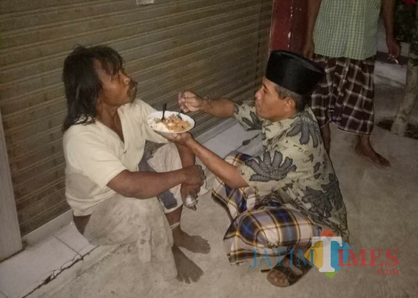 Kepala Desa Banjarejo, Kecamatan Rejotangan, Zaenuddin Jawahir saat menyuapi gelandangan. / Foto : Istimewa / Tulungagung TIMES