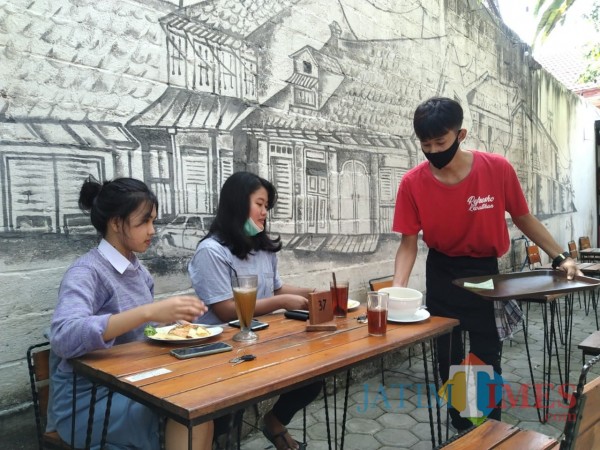 Pengunjung cafe menikmati makanan yang disajikan oleh pelayan (Joko Pramono for Jatim TIMES)
