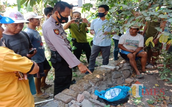 Polisi menunjuk kain kafan yang ditemukan warga. (Foto : Adi Rosul / JombangTIMES)