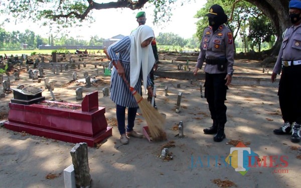 Warga bersihkan makam setelah terjaring razia Yustisi. (Foto: Adi Rosul/ JombangTIMES)