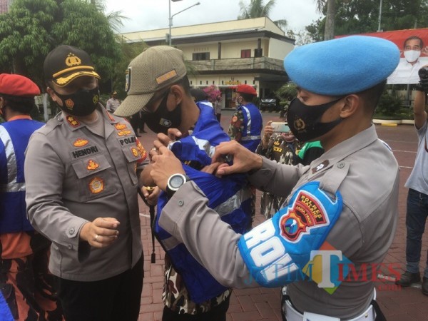 Kapolres Malang AKBP Hendri Umar (paling kiri) saat mengenakan rompi kepada relawan protokol kesehatan (Foto : Ashaq Lupito / MalangTIMES)