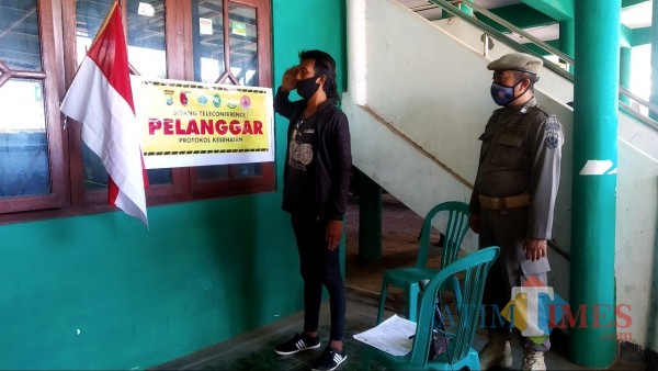 Salah seorang pelanggar Protkes sedang menjalani sanksi sosial dan Distampel di bagian lengan (Foto: Abror Rosi/JatimTimes)