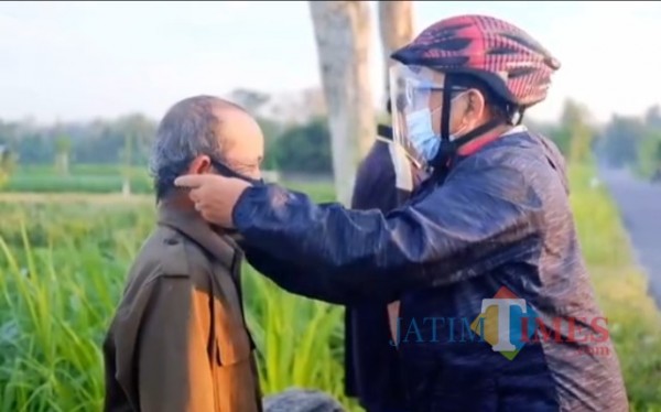 Rijanto membagi dan memakaikan masker kepada warga yang beraktivitas di sawah