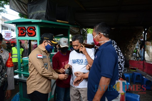 Wali Kota Malang Sutiaji (bertopi) saat membagikan masker kepada masyarakat di kawasan Pasar Burung Splendid, Selasa (29/9). (Arifina Cahyanti Firdausi/MalangTIMES).