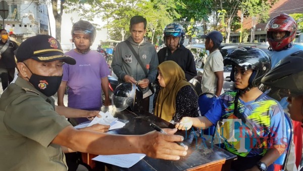 Petugas saat melakukan pendataan kepada sejumlah warga yang melanggar protokol kesehatan dengan tidak memakai masker (Foto:Rozy/JatimTimes.com)