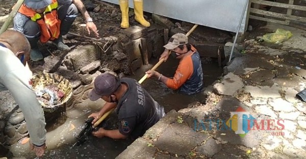Personel Satgas DPUPRPKP saat melakukan normalisasi saluran drainase di Jalan Raya Arjowinangun (Anggara Sudiongko/ MalangTIMES)