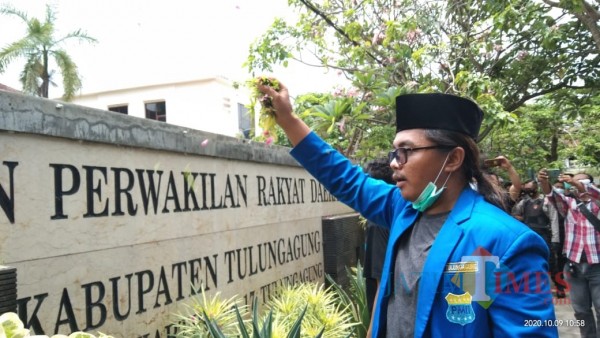 Ketua PMII Tulungagung, M. Afifudin saat menaburkan bunga di gedung DPRD Tulungagung (Joko Pramono for Jatim TIMES)