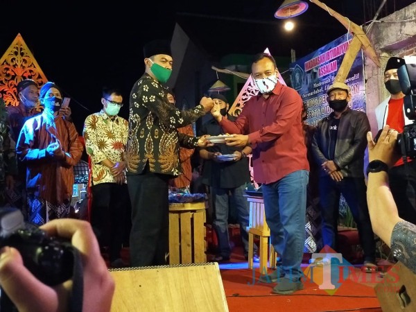 Kepala Dinas Pariwisata Kota Batu Arief As Siddiq memberikan potongan tumpeng kepada kepala Desa Beji Deny Cahyono. (Foto: Muklas/JatimTIMES)