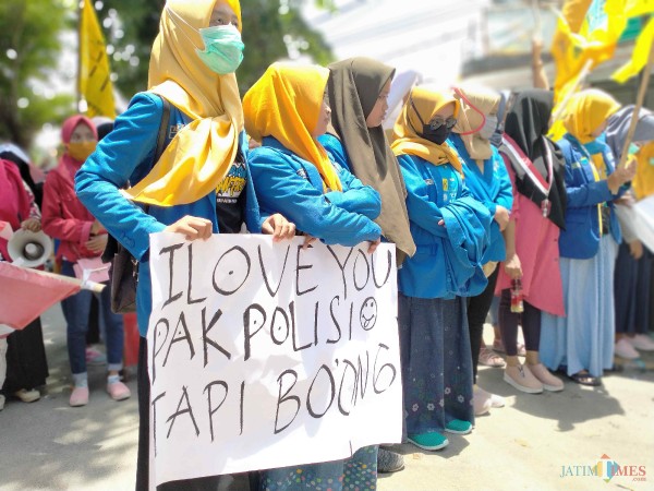 Aktivis perempuan dari Kopri PMII dan GMNI Sumenep membentangkan poster 'I LOVE Pak Polisi Tapi Bohong' saat demo di Mapolres (Foto: Syaiful Ramadhani/ JatimTIMES)