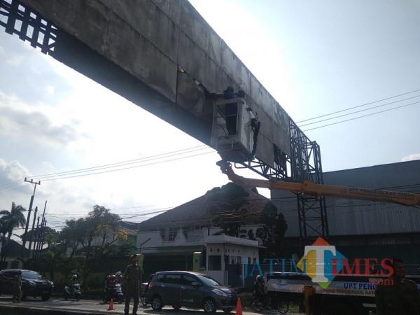 Petugas satpol PP saat membenahi papan reklame dan penertiban pemasangan iklan liar menggunakan truk crane. (Foto : Satpol PP Pemkab Malang for MalangTIMES)