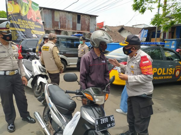 Kapolsek Sukun Kompol Suyoto saat memberikan reward terhadap masyarakat yang patuh pada protokol kesehatan (Ist)