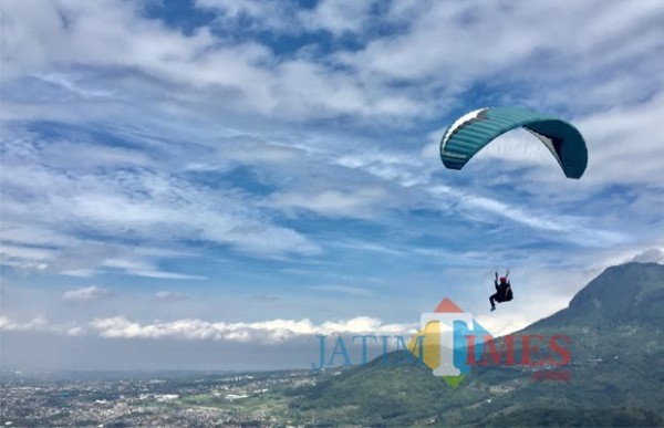 Atlet paralayang saat terbang di atas langit Kota Batu. (Foto: Irsya Richa/MalangTIMES)