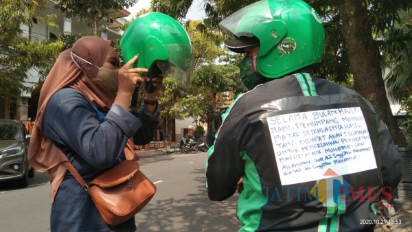 Fachruroziy saat mendapat order, terlihat jaket yang beri pengumuman tarif sukarela (Joko Pramono for Jatim TIMES)