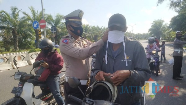 Kasat Lantas Polres Kediri AKP Bobby Mochamad Zulfikar ketika mengenakan masker kepada pengguna jalan. (Foto: Bams Setioko/JatimTIMES)