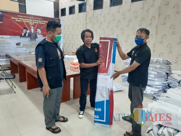 Koordinator Divisi Sosialisasi Pendidikan Pemilihan dan Sumber Daya Manusia KPU Kabupaten Malang Marhaendra Pramudya Mahardika (tengah) saat menyerahkan APK ke LO salah satu paslon. (Foto: Dok. JatimTimes)