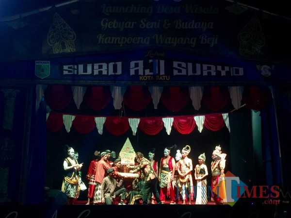 Kepala Dinas Pariwisata Kota Batu Arief As Siddiq daat menancapkan gunungan wayang di atas pelepah pisang di Kampoeng Wayang Beji, Minggu (15/11/2020) malam. (Foto: Irsya Richa/MalangTIMES)