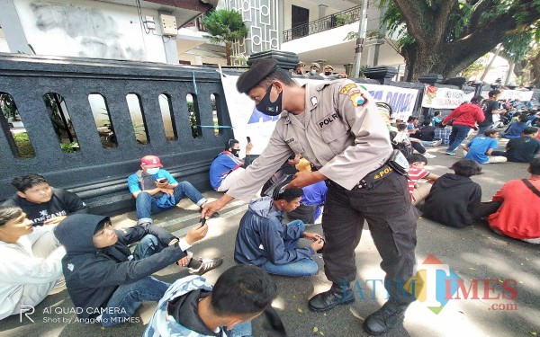 Personel kepolisian yang membagikan masker pada Aremania yang tak mengenakan masker (Anggara Sudiongko/MalangTIMES)