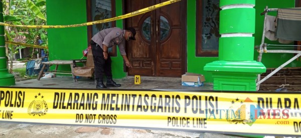 Petugas saat berada di depan rumah korban yang masih dipasangi police line. (Joko Pramono for Jatim TIMES)