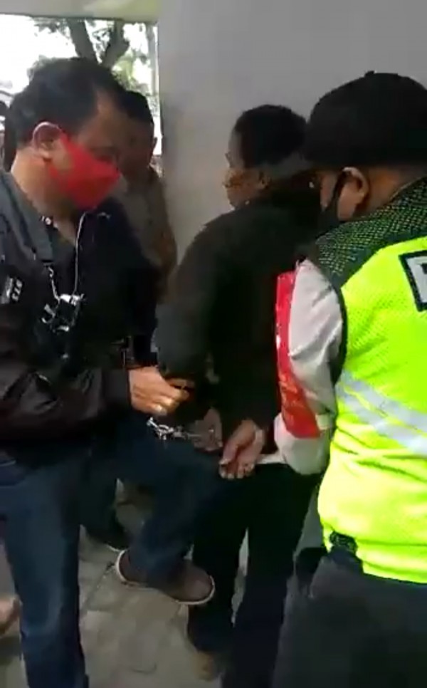 Polisi saat menangkap terduga pelaku penganiayaan dan pembakaran (potongan video)