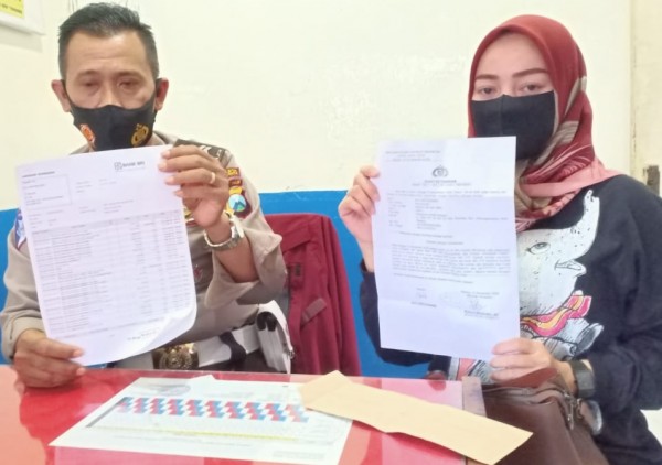 Ayu Kartika (kiri), korban yang dikuras rekeningnya oleh oknum penipu menunjukkan surat bukti laporan kepolisian (ist)