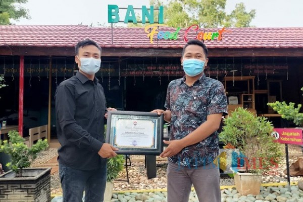 Manager Bani Food Court Luthfiadi saat menerima piagam penghargaan dari ketua Jurnalis Center Pamekasan (Foto:Rozy/JatimTIMES.com)