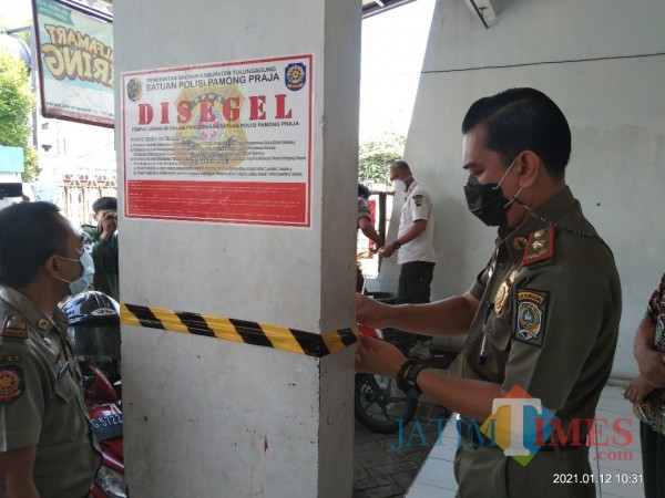 Satpol PP Tulungagung saat memasang segel dan pita di toko modern di Jalan Semeru Tulungagung (Joko Pramono for Jatim TIMES)