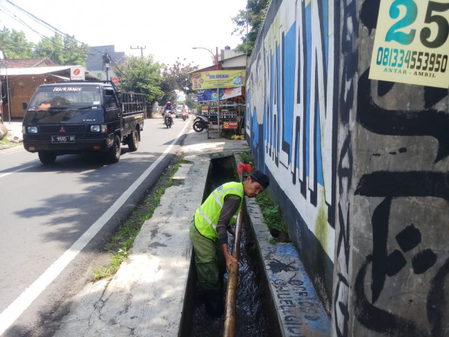 Nampak para personil Satgas DPUPRPKP setengah mengangkat bambu sepanjang kurang lebih 5 meter dari saluran air (Ist)