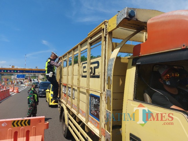 Petugas kepolisian sedang melakukan pengecekan pada bak truk.