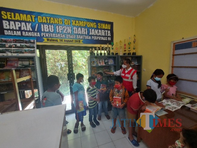 Anak-anak saat menikmati koleksi buku dari Kampung Sinau, Kelurahan Sawojajar, Kecamatan Kedungkandang, Kota Malang.