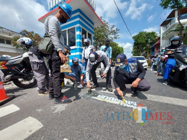 Petugas Dinas Perhubungan Kota Malang saat melakukan pembersihan coretan bernada provokatif.