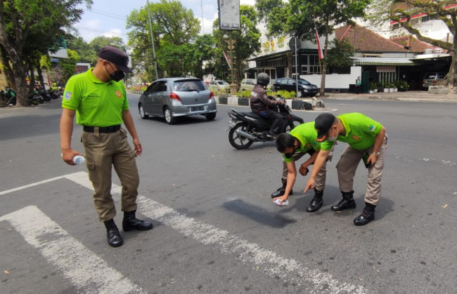 Petugas Satgas Trantibum Satpol PP Kota Malang saat melakukan pembersihan coretan di marka jalan sekitar Monumen Chairil Anwar. 