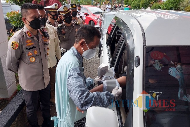 Petugas Dokkes Polresta Malang Kota saat melakukan pengecekan tensi darah calon peserta vaksinasi drive thru.