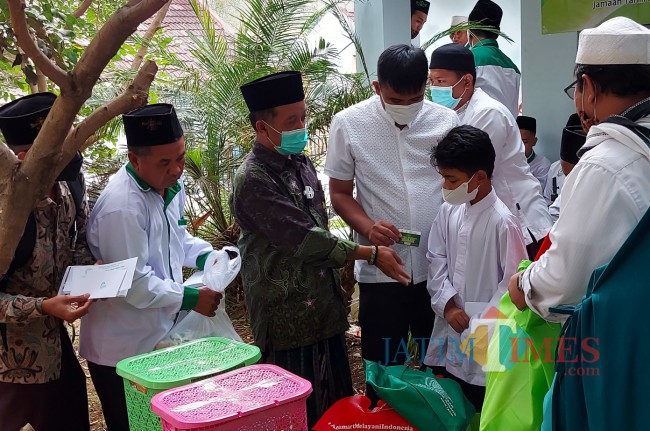 KH Noor Sodiq Askandar saat memberikan bantuan kepada anak yatim.