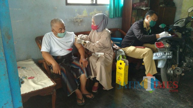 Petugas vaksinator Kecamatan Tajinan didampingi beberapa unsur Muspika saat meakukam vaksinasi door to door.(Foto: Riski Wijaya/MalangTIMES).