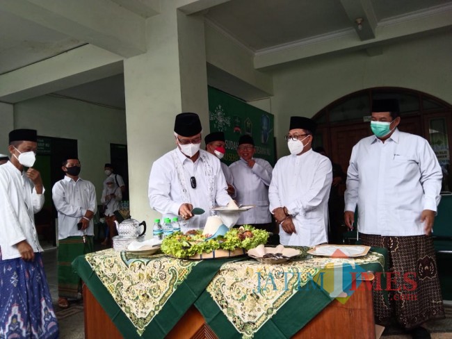 Proses pemotongan tumpeng oleh Ketua Tanfidziyah PCNU Kota Malang KH Isroqunnajah yang diberikan kepada Wali Kota Malang Sutiaji. 