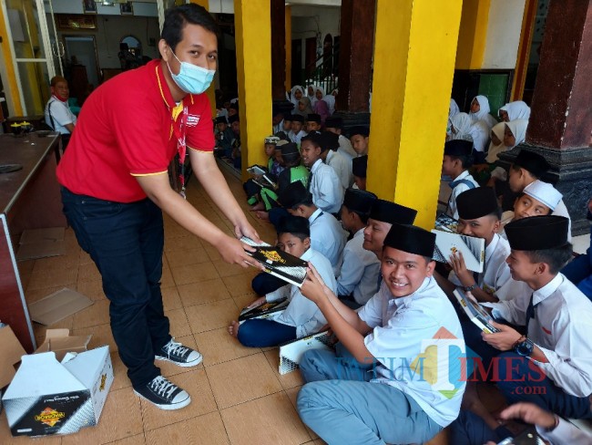 Salah satu pegawai Alfamart menyerahkan bantuan sarung kepada santri Pondok Pesantren Nur Ilahi Tajinan.